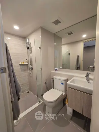 Modern bathroom with glass shower and sleek fixtures in contemporary apartment.
