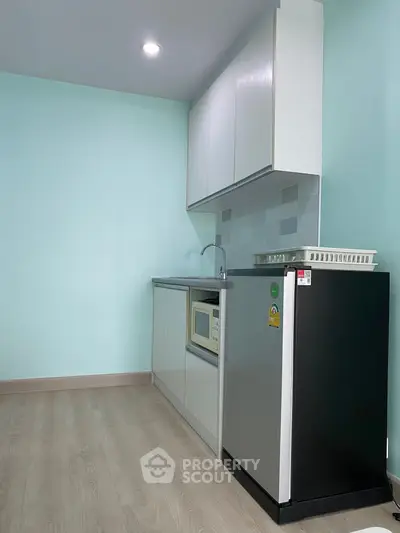 Modern compact kitchen with sleek cabinetry and appliances in a minimalist design.