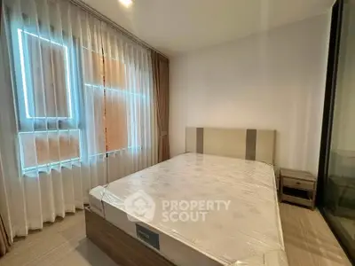 Spacious bedroom with large window and modern furnishings in a stylish apartment.
