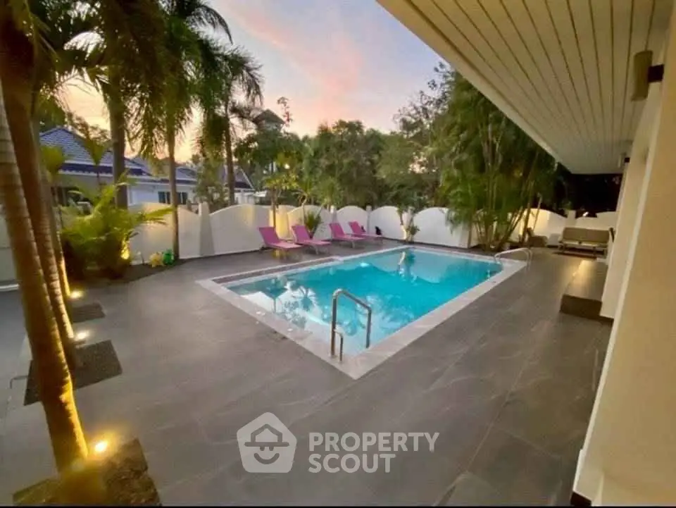 Luxurious outdoor pool area with elegant lighting and lush greenery, perfect for relaxation and entertainment.