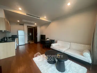 Modern living room with open kitchen, hardwood floors, and stylish furniture in a cozy apartment.