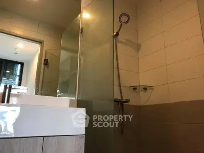Modern bathroom with glass shower and sleek vanity in contemporary apartment.