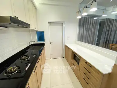 Modern kitchen with sleek black countertops and gas stove in a stylish apartment.