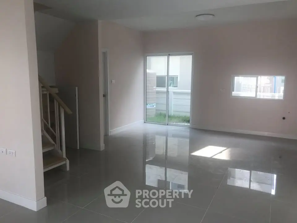 Spacious modern living room with glossy tile flooring and sliding glass doors leading to a small garden.
