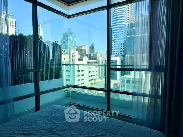 Luxurious bedroom with stunning city view through floor-to-ceiling windows.