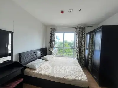 Spacious bedroom with large window and modern furnishings, offering a serene view.