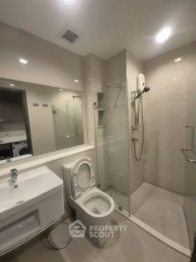 Modern bathroom with glass shower and sleek fixtures in contemporary apartment.