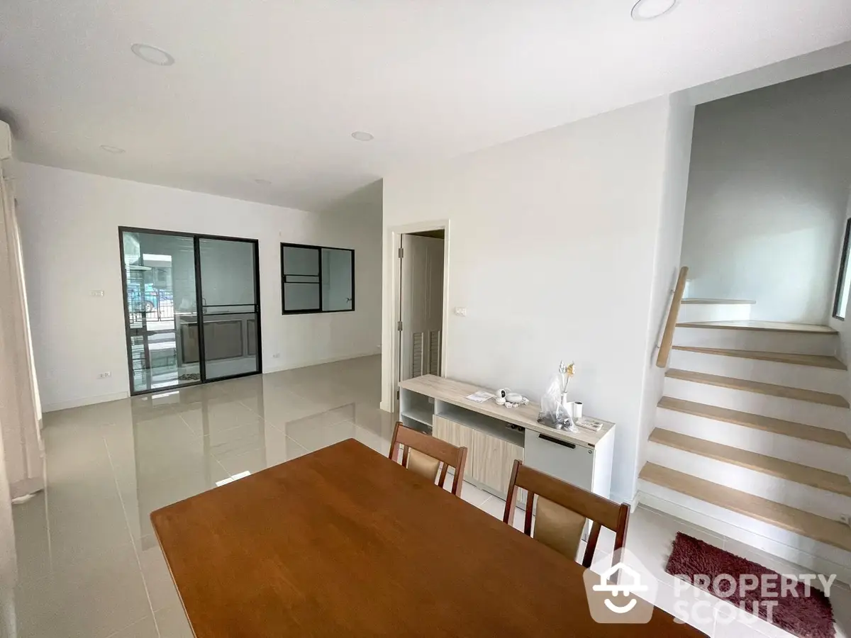 Spacious multi-level home with gleaming tiled floors, large dining area, and modern staircase leading to upper levels, perfect for family living.