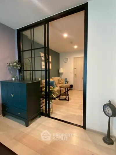 Stylish living room with modern decor and glass partition, featuring cozy seating and elegant lighting.