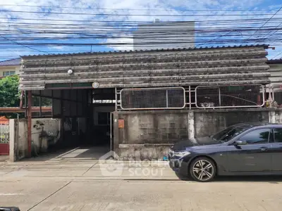 Industrial-style garage with corrugated metal facade and parked car in urban setting.