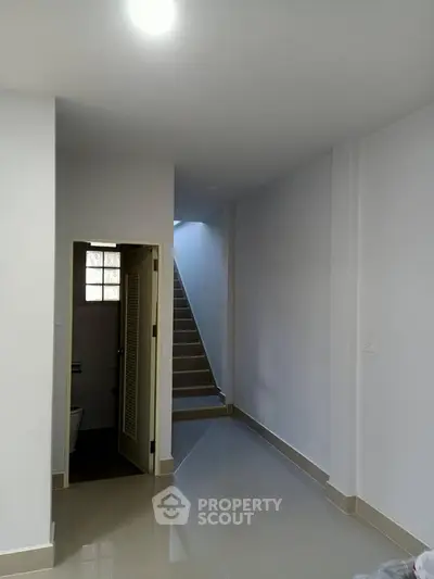 Spacious hallway with staircase and bathroom entry in modern home