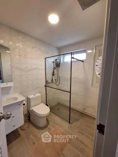 Modern bathroom with glass shower, sleek fixtures, and elegant tile design.