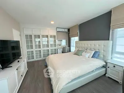 Spacious bedroom with elegant decor and ample natural light, featuring a large bed and stylish furnishings.