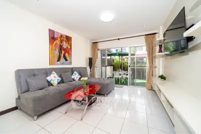 Modern living room with stylish decor and garden view, featuring a sleek gray sofa and vibrant artwork.