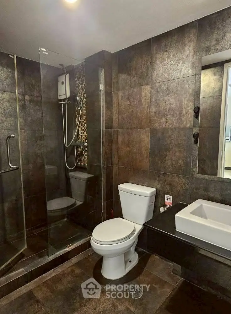 Modern bathroom with sleek dark tiles and glass shower enclosure