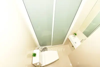 Modern minimalist bathroom with sleek fixtures and frosted glass door.