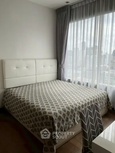 Modern bedroom with large window and city view, featuring stylish decor and natural light.
