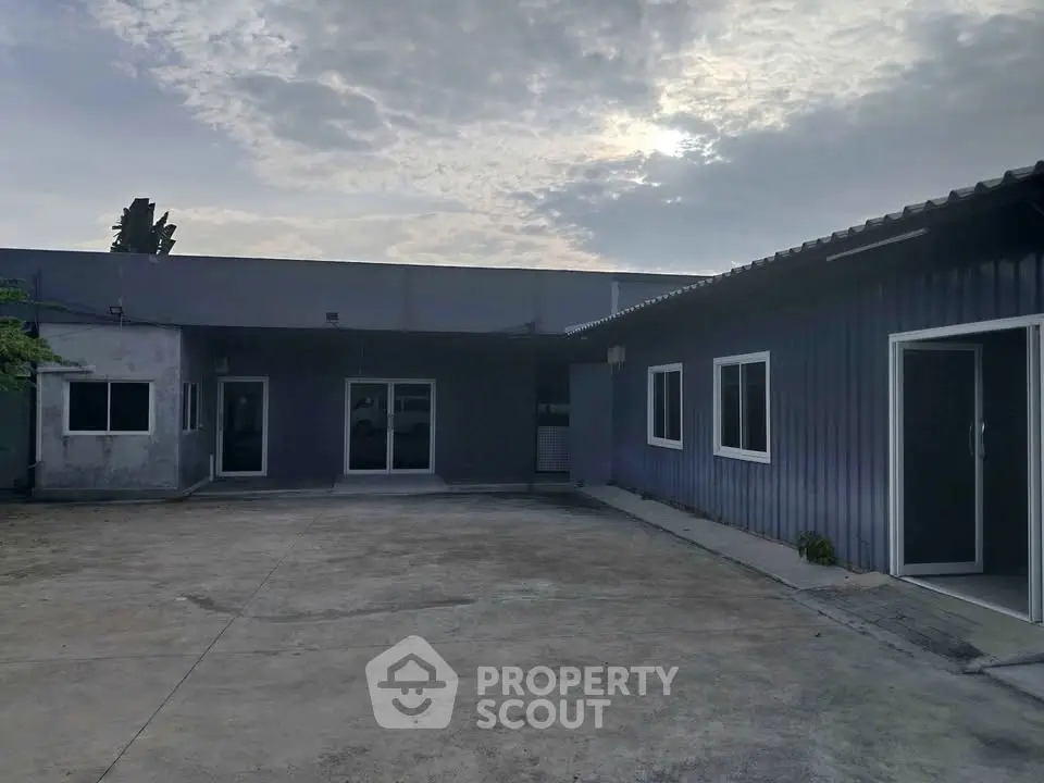 Spacious industrial warehouse exterior with ample parking space and modern design.