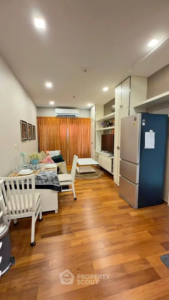 Modern living room with wooden flooring, stylish furniture, and large window with curtains.