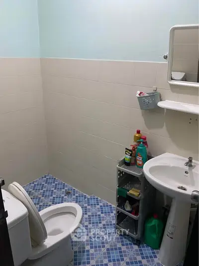 Compact bathroom with blue-tiled floor and essential fixtures, ideal for small spaces.