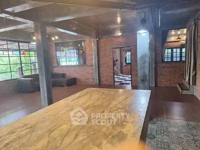 Spacious industrial-style living area with exposed brick and large windows.