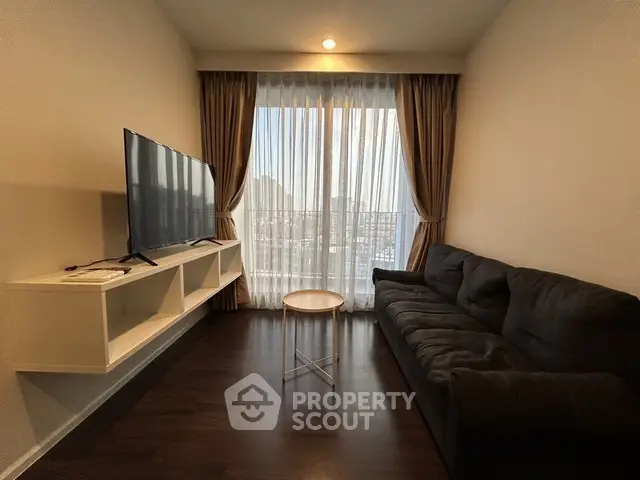 Modern living room with large TV, cozy sofa, and balcony view.