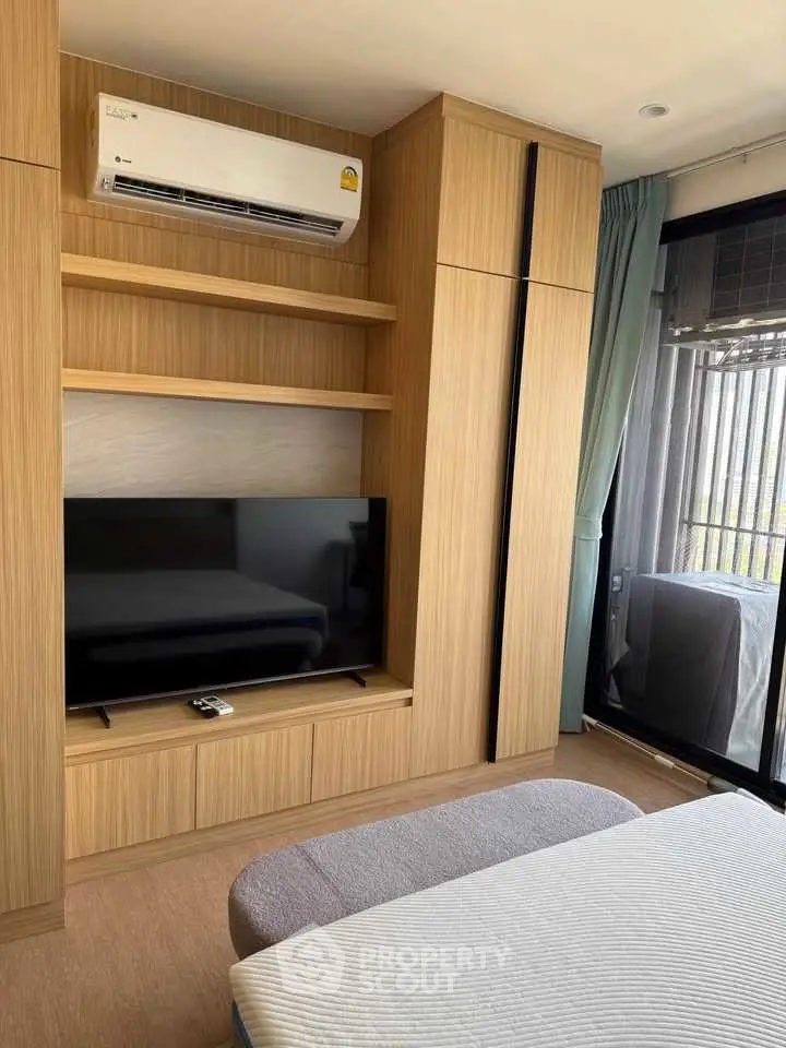 Modern bedroom with built-in wooden wardrobe and large TV, featuring a balcony view.