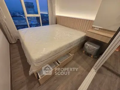 Modern bedroom with city view, featuring a bed with storage drawers and sleek wooden flooring.