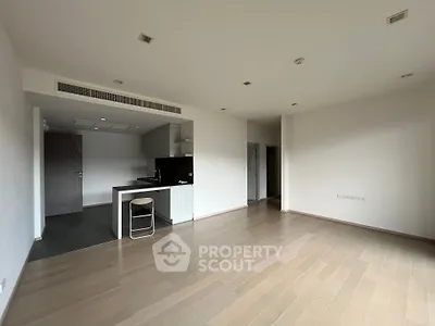 Spacious open-plan living area with sleek hardwood floors and a modern kitchen featuring a built-in oven and ample cabinetry, perfect for entertaining.