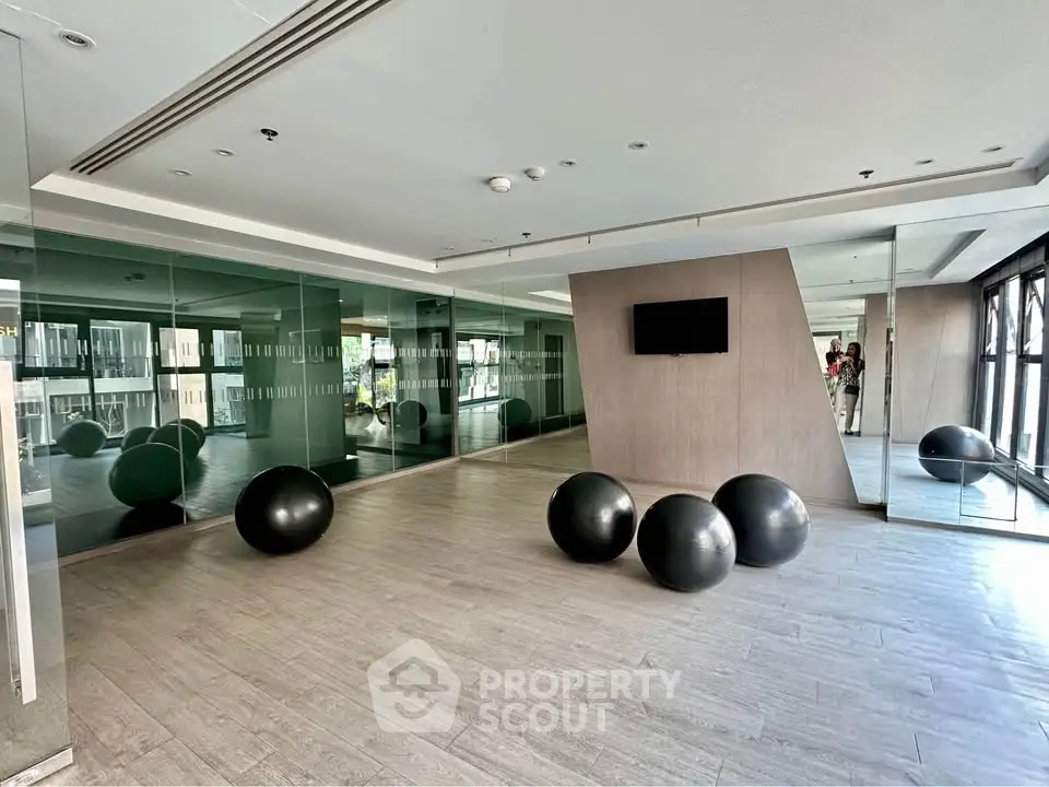 Spacious modern gym with mirrored walls and exercise balls in luxury building