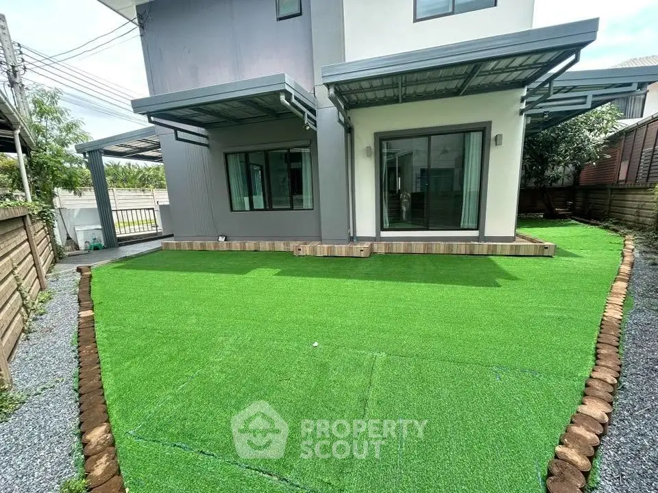 Modern house exterior with artificial grass and covered patio area