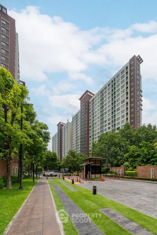 Modern high-rise apartment buildings with lush green surroundings and clear blue sky.