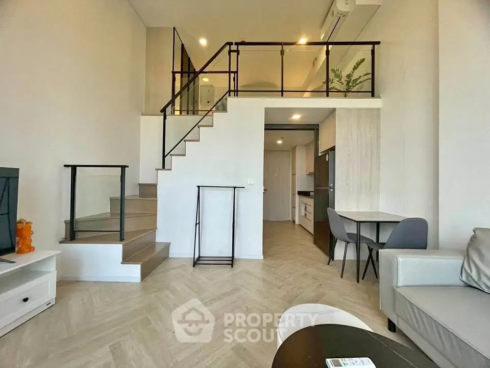 Modern loft-style living room with high ceiling and elegant staircase