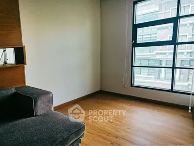Spacious living room with large window and wooden flooring in modern apartment.