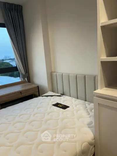 Cozy bedroom with plush mattress and elegant headboard, featuring a scenic window view and built-in shelving.