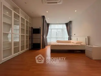 Spacious bedroom with large windows and wooden flooring