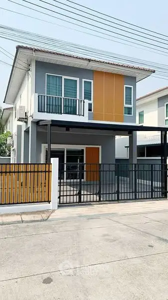 Modern two-story house with sleek design and balcony in suburban neighborhood.