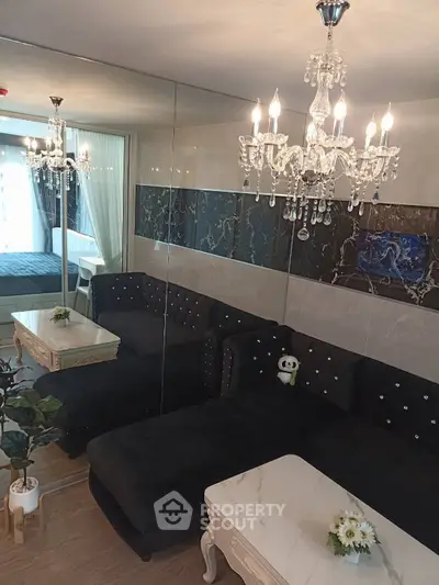 Luxurious living room with elegant chandeliers and plush black sofa, featuring mirrored walls and stylish decor.