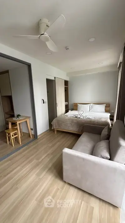 Modern bedroom with cozy bed, sofa, and wooden flooring in a stylish apartment.