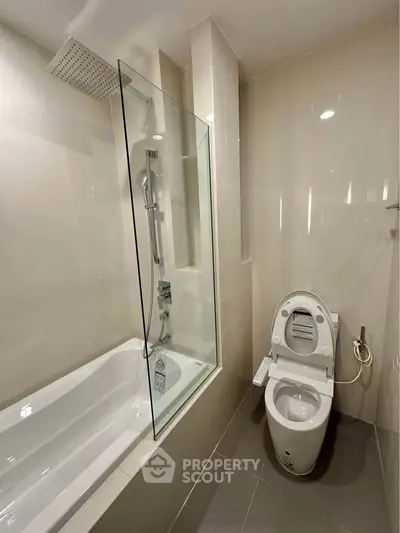 Modern bathroom with sleek design featuring a bathtub and advanced toilet system.