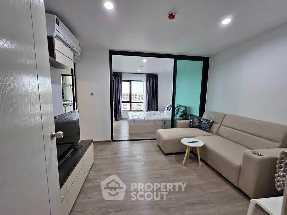 Modern living room with beige sofa and open view to bedroom in stylish apartment