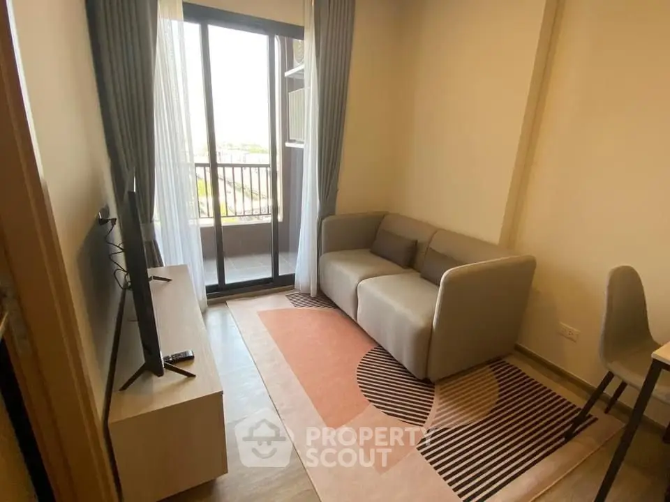 Cozy living room with modern sofa and TV, leading to a balcony with a view.