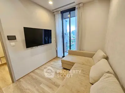 Modern living room with cozy beige sofa and wall-mounted TV, featuring a balcony with city view.