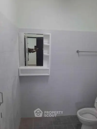 Minimalist bathroom with wall-mounted mirror and toilet in a modern apartment.