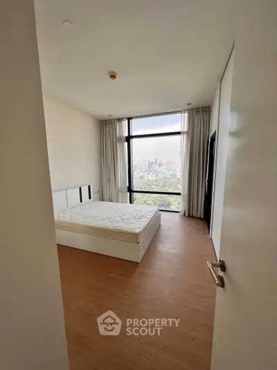 Spacious bedroom with city view and large window, featuring a comfortable bed and modern design.