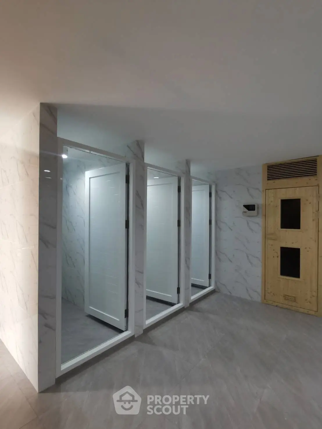 Modern shared bathroom area with sleek design and marble finishes in a contemporary building.