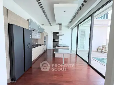 Luxurious modern kitchen with sleek design and poolside view, featuring high-end appliances and elegant wooden flooring.