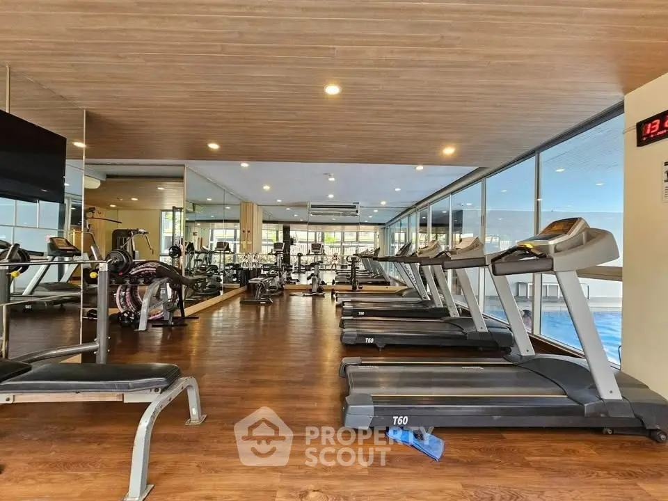 Spacious modern gym with state-of-the-art equipment and wooden flooring in a luxury residential building.