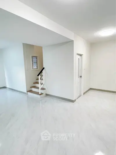 Spacious modern interior with sleek staircase and glossy tiled flooring, perfect for contemporary living.
