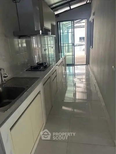 Modern kitchen with sleek design and gas stove, featuring a bright open layout and large windows.